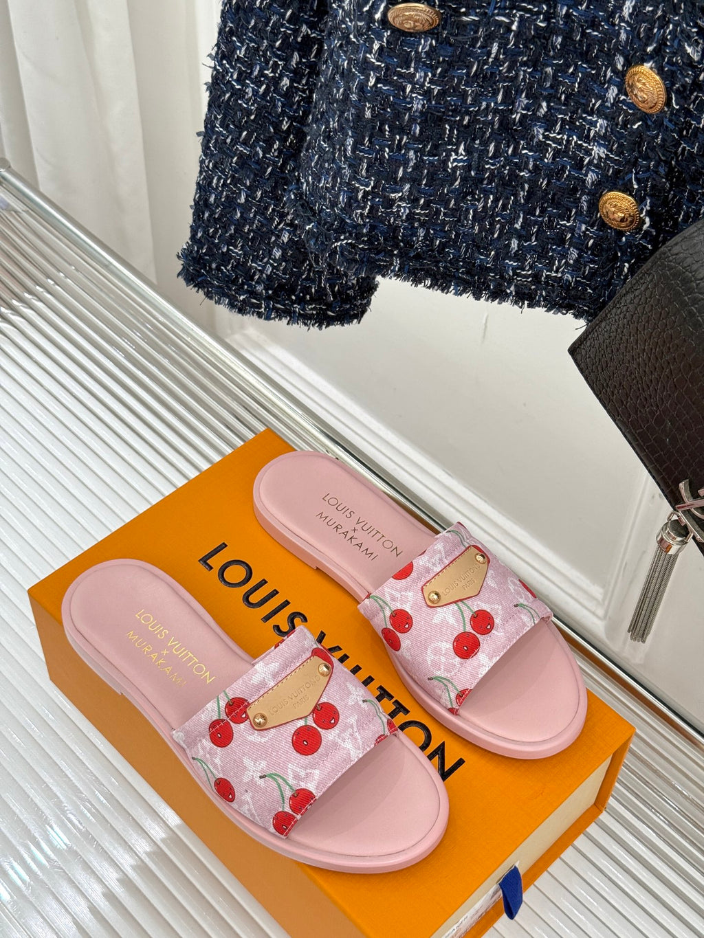 Pair of pink cherry-print slide sandals with gold-tone buckle and light pink straps
