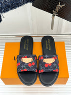 Louis Vuitton women's black slide sandals with cherry-print straps and beige logo tabs.