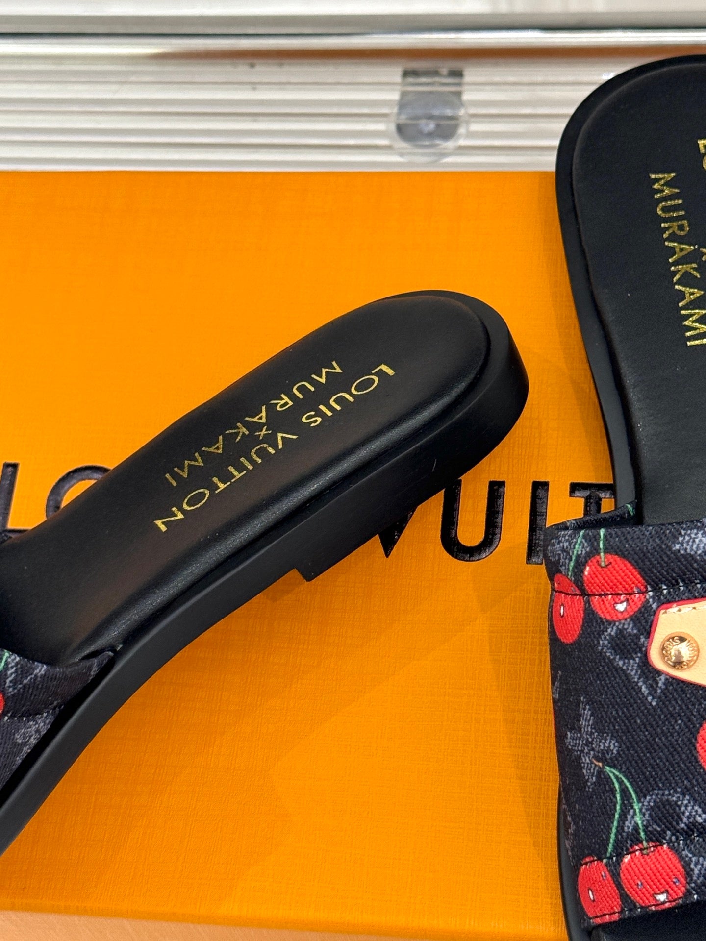 Louis Vuitton women's black slide sandal close-up of footbed with gold text.