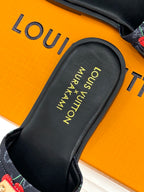 Louis Vuitton women's slide sandal close-up of black footbed with gold text.