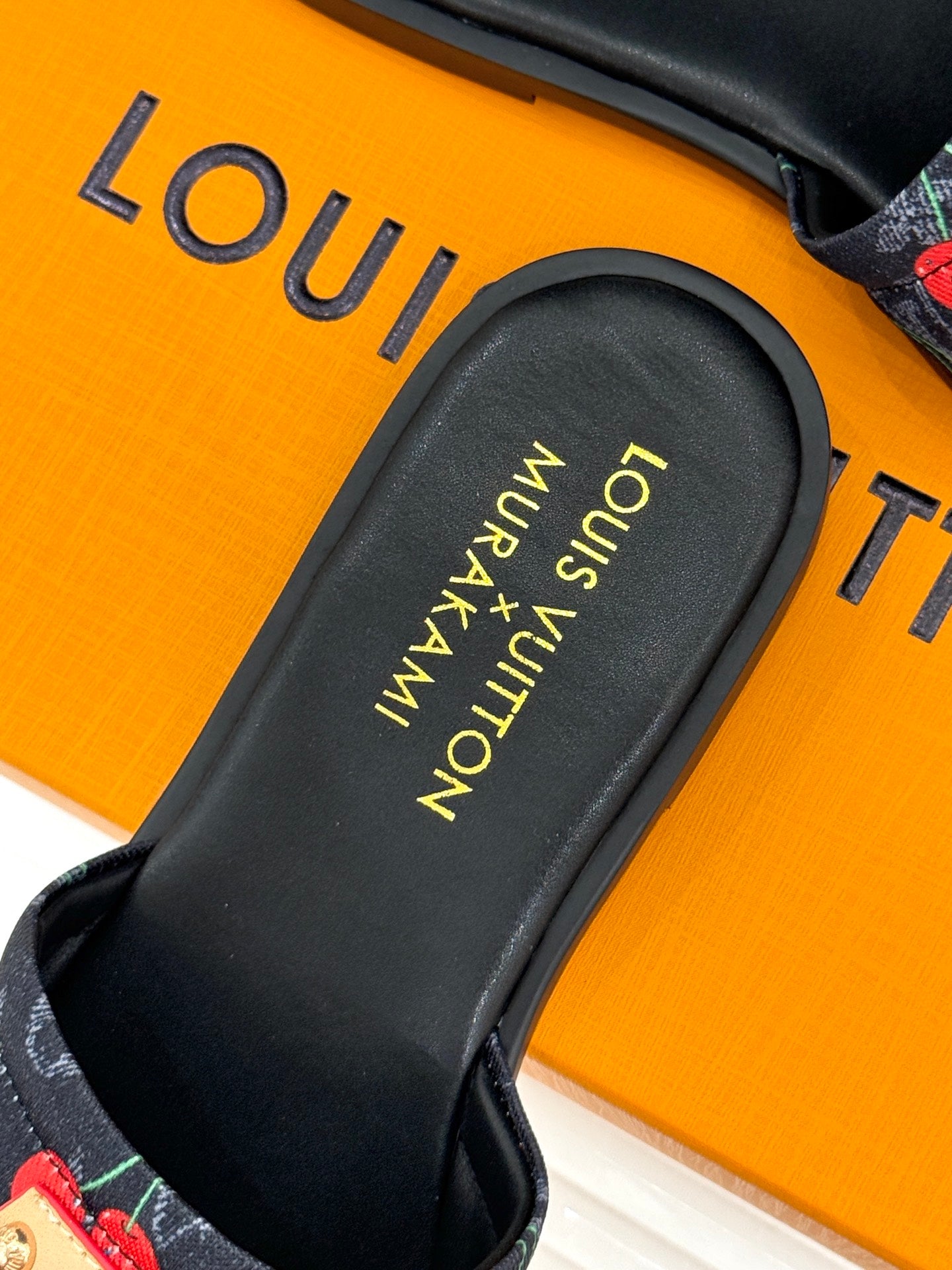 Louis Vuitton women's slide sandal close-up of black footbed with gold text.
