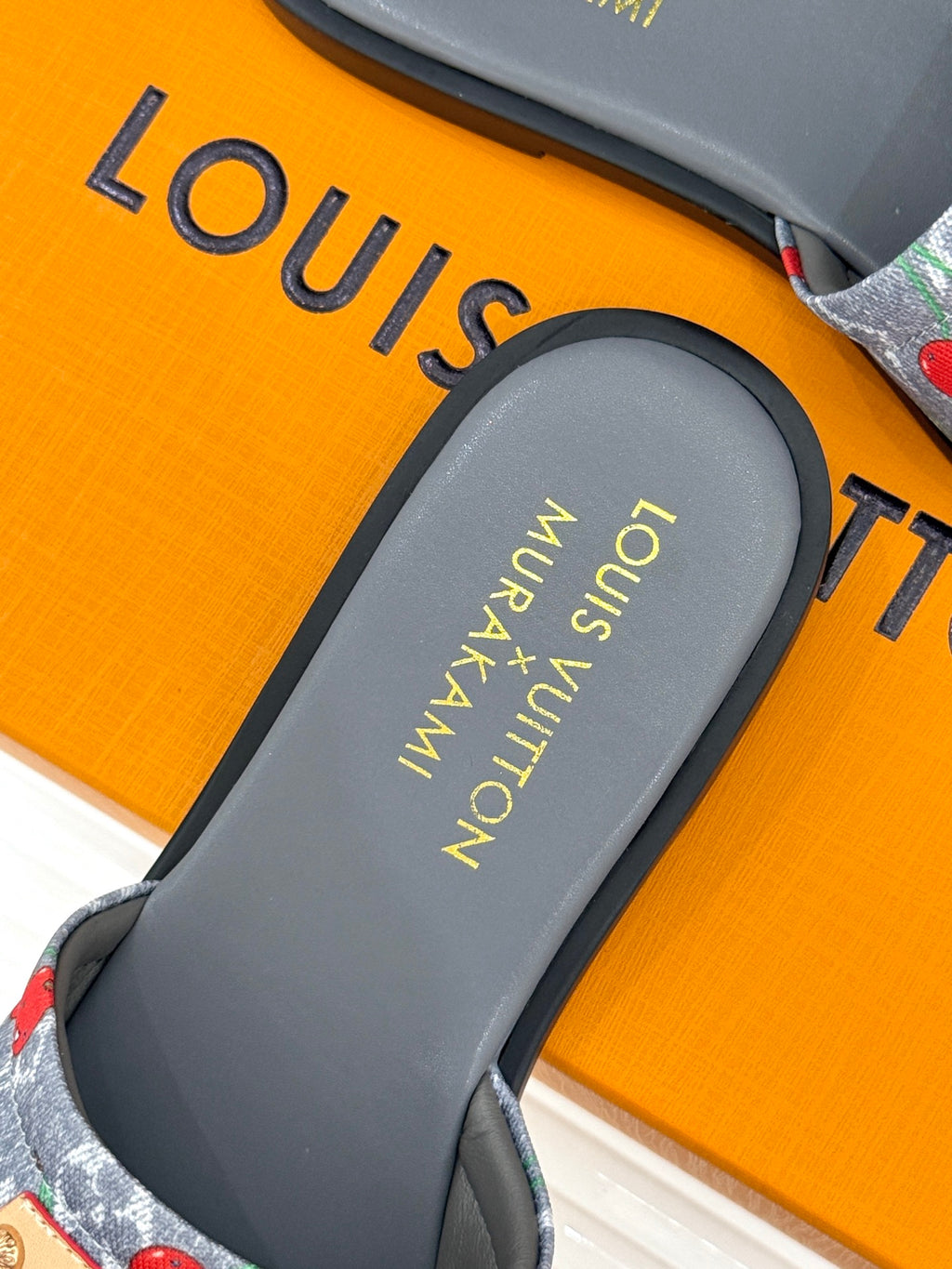 Women’s slide sandals close-up: gray footbed with gold logo text
