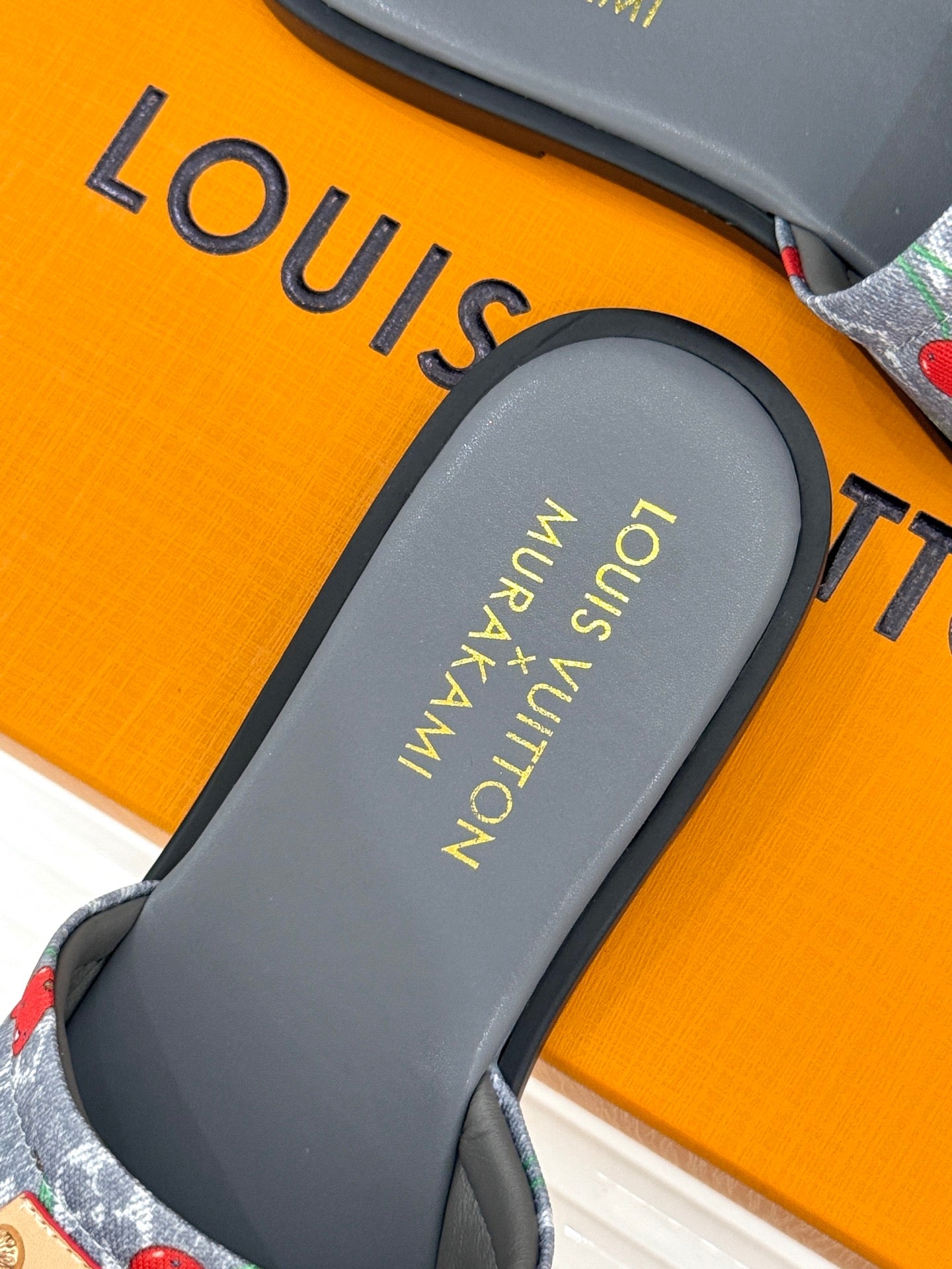 Women’s slide sandals close-up: gray footbed with gold logo text