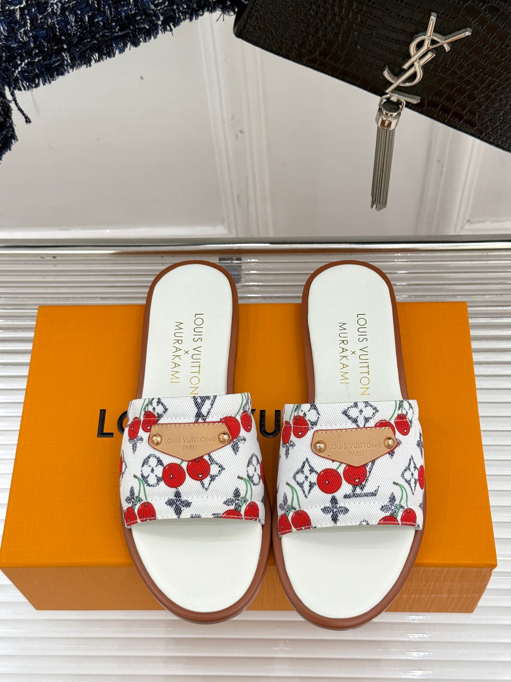 Pair of white ladies slide sandals with cherry print straps and brown footbed