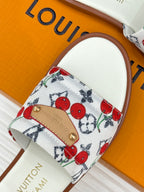 Ladies slide sandal showing white cherry-print strap with gold logo patch