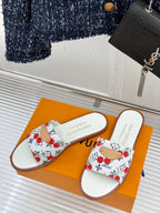 Pair of ladies slide sandals with white cherry-pattern straps and brown edges