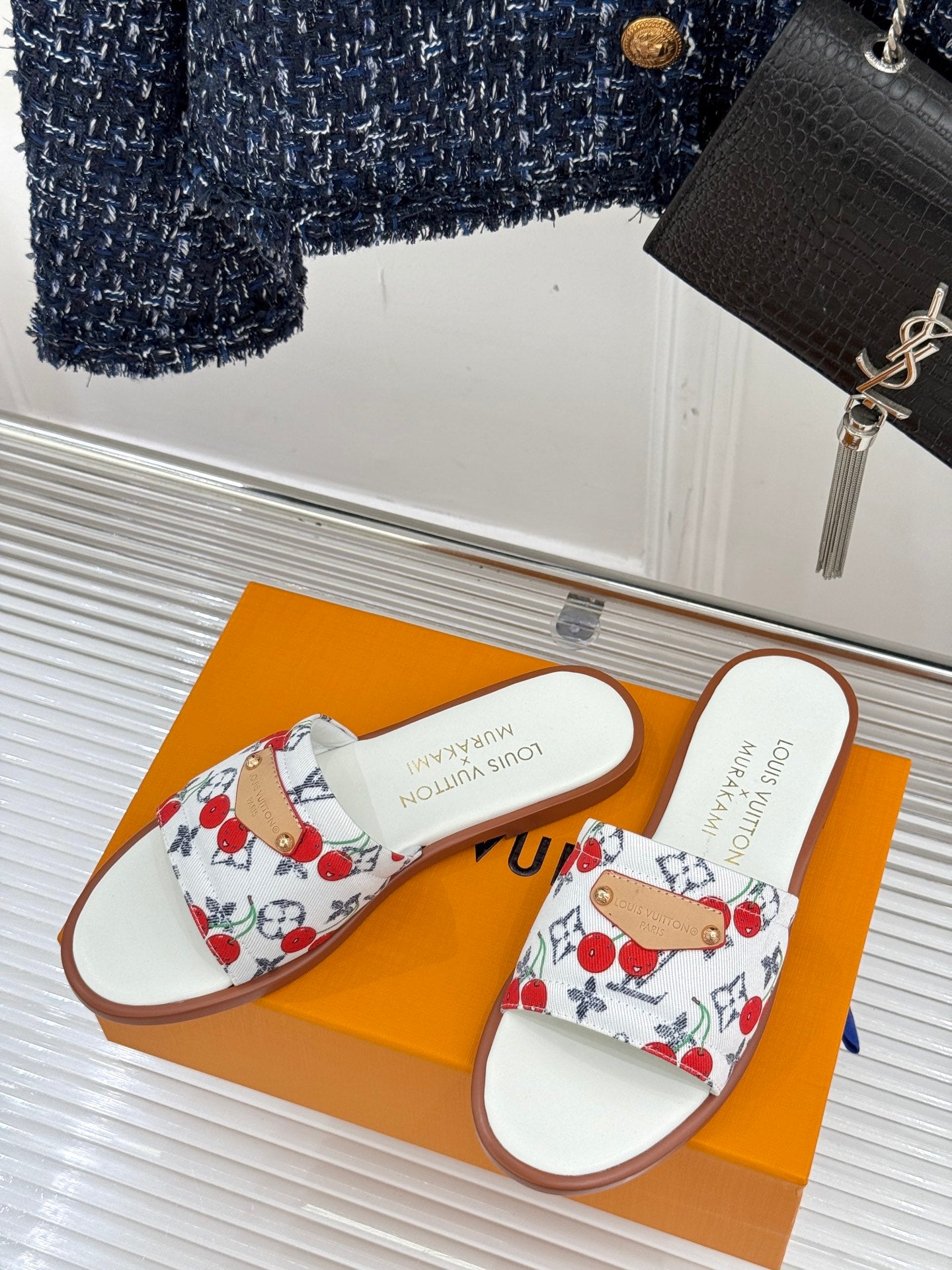 Pair of ladies slide sandals with white cherry-pattern straps and brown edges