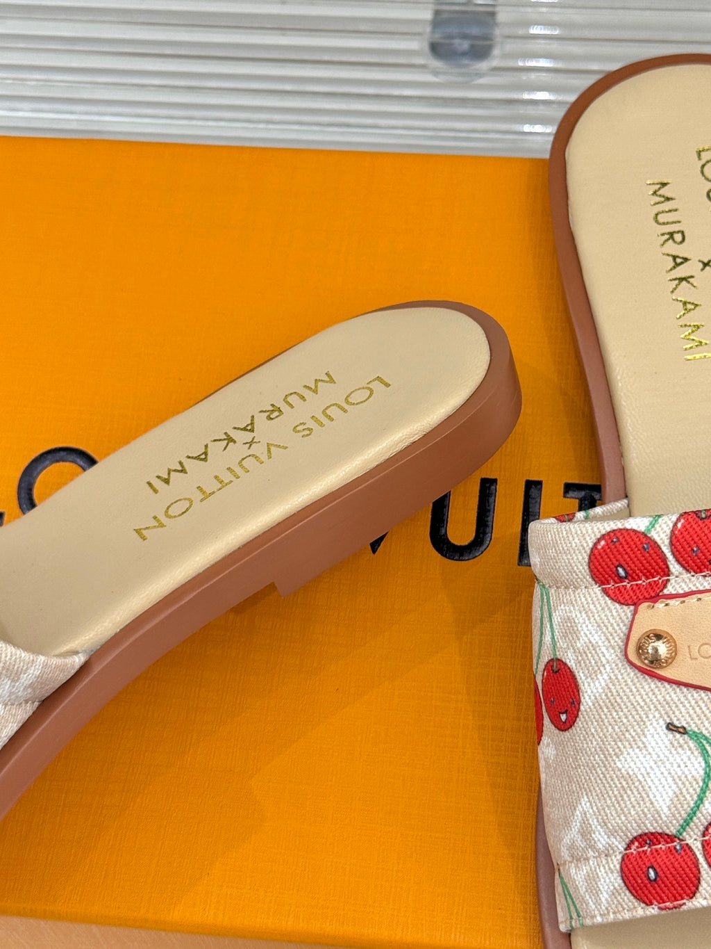 Louis Vuitton slide sandal footbed with gold logo text and cherry-pattern strap