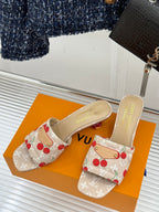 Beige cherry-print slide mule sandals with gold logo buckle detail.