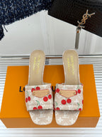 Beige cherry-print slide sandals with gold-tone logo insoles and buckle.