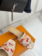 Beige cherry-print mule sandals with gold-tone logo footbed and fabric strap.