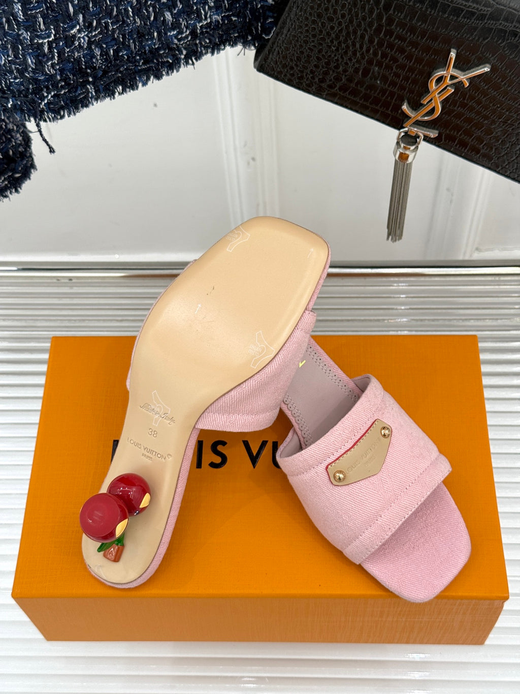 Light pink slide sandal with gold buckle plate on orange retail box