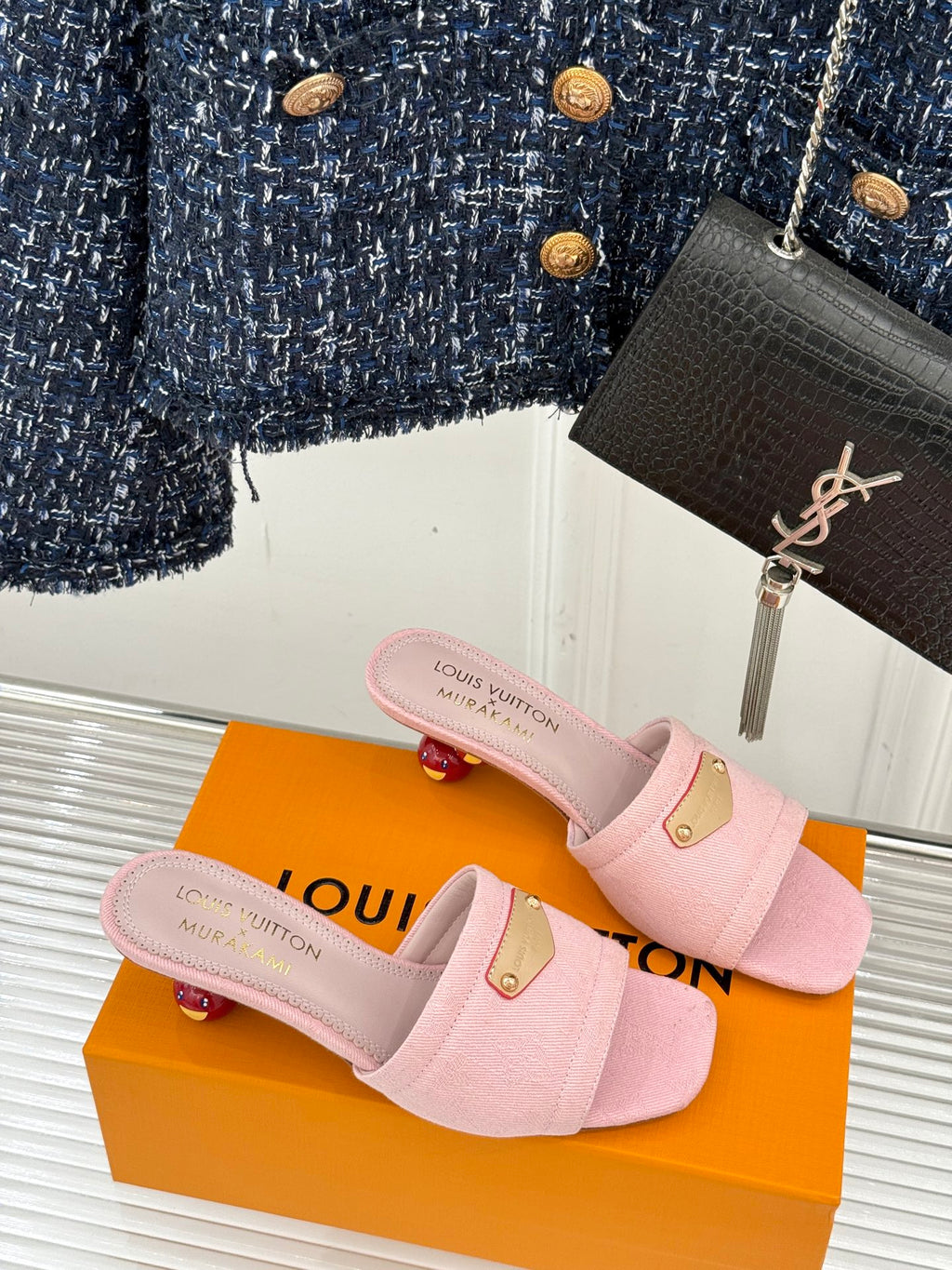 Pink slide sandals with gold buckle detail on straps, on retail box