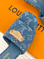 Close-up: blue Monogram slide sandal with tan logo patch and stitched straps