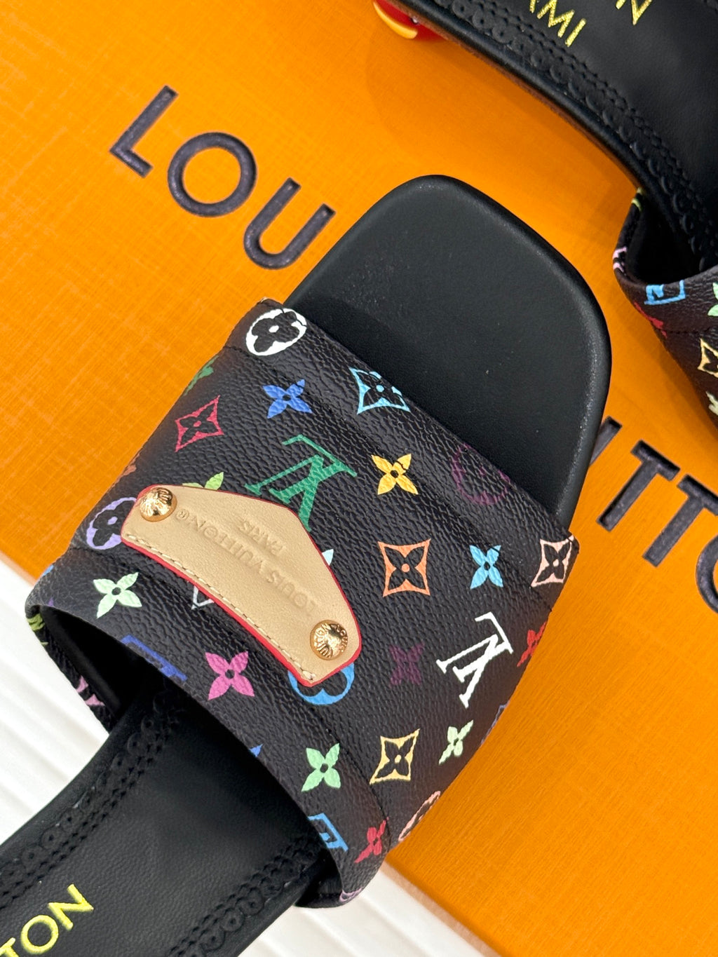 Black slide sandal with multicolor monogram-pattern strap and tan tab detail