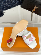 White slide sandals with pink flower print, gold buckle strap, beige sole