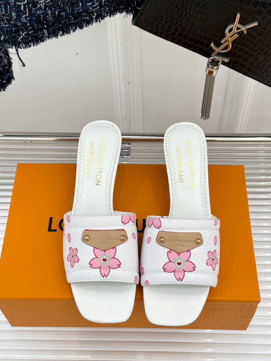 Pair of white slide sandals with pink flower print and gold buckle straps