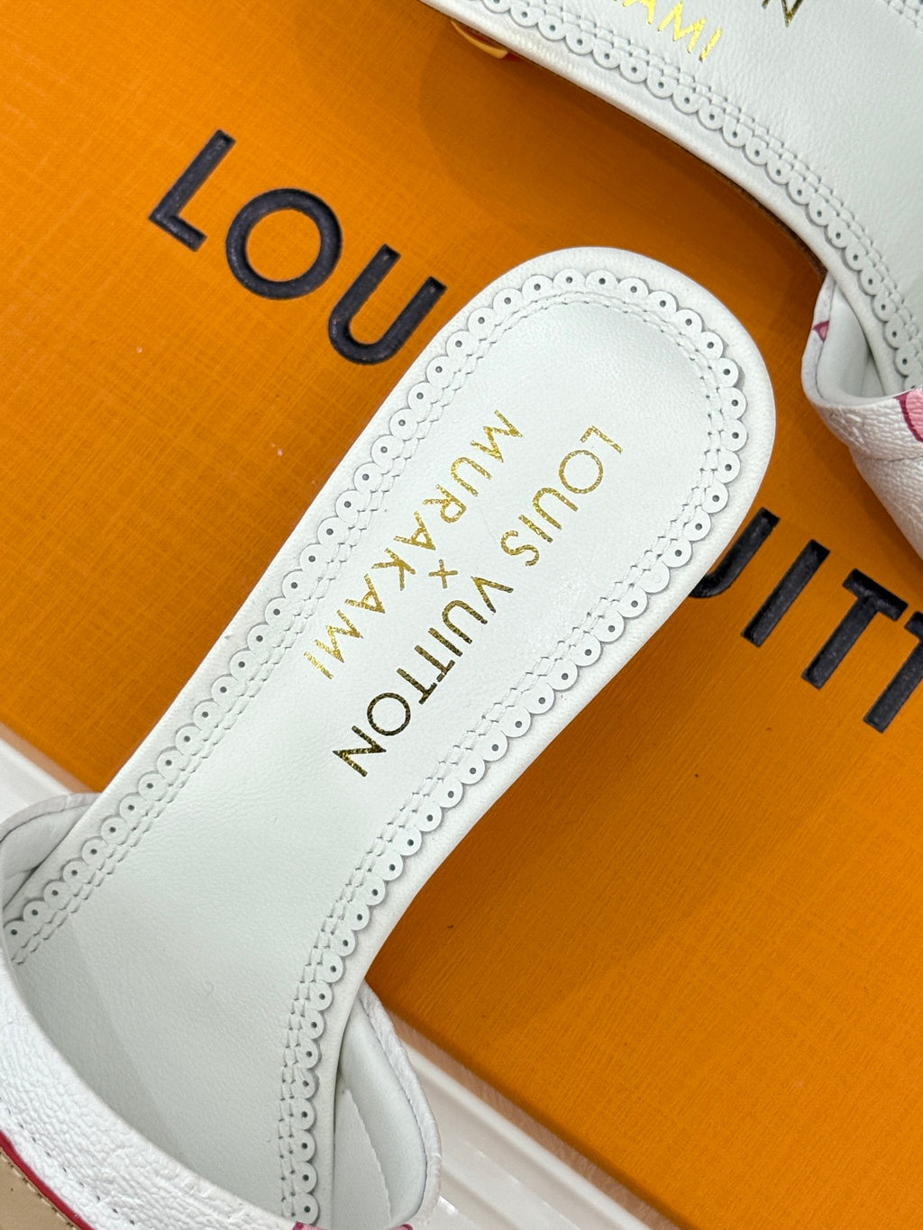 White slide sandal with insole showing gold 'Louis Vuitton' lettering