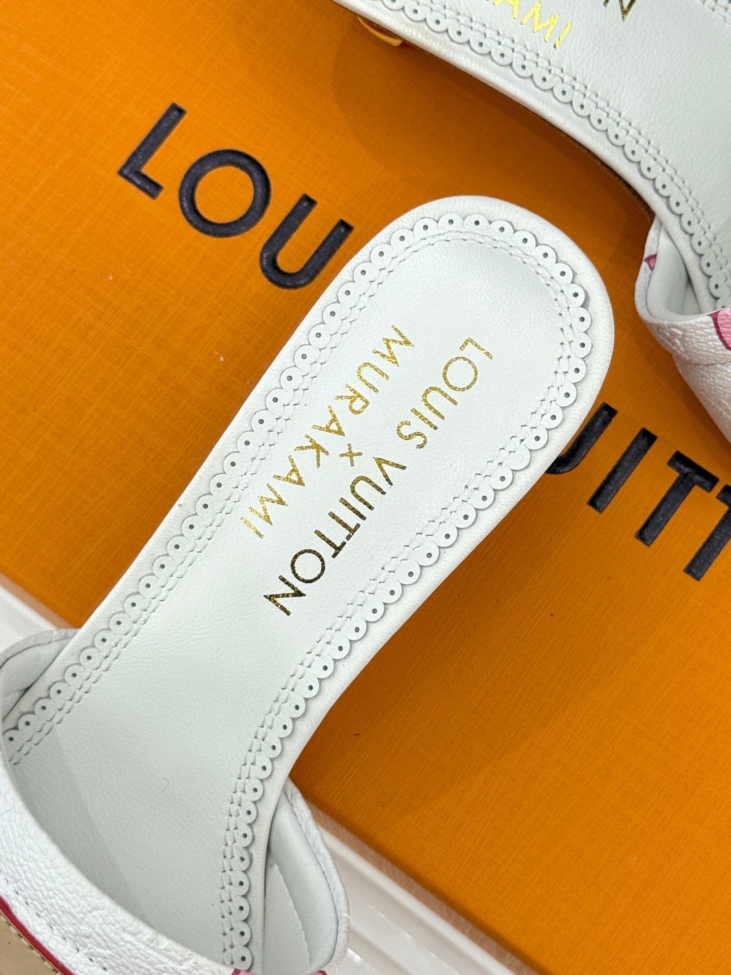 White slide sandal with insole showing gold 'Louis Vuitton' lettering