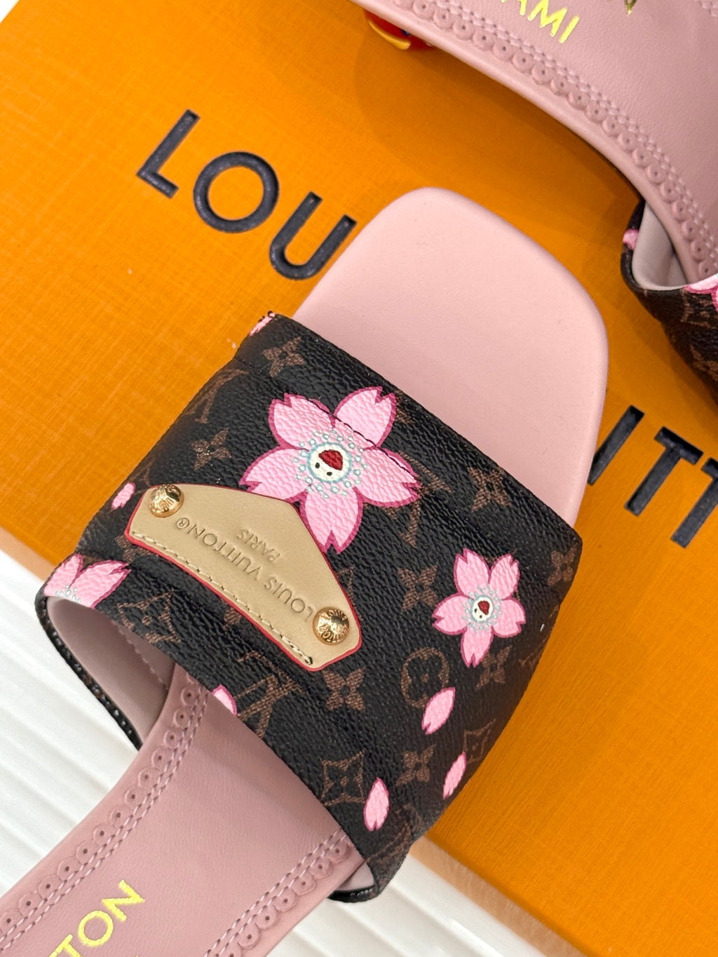 Louis Vuitton sandal strap detail: black floral print with pink flower bow trim