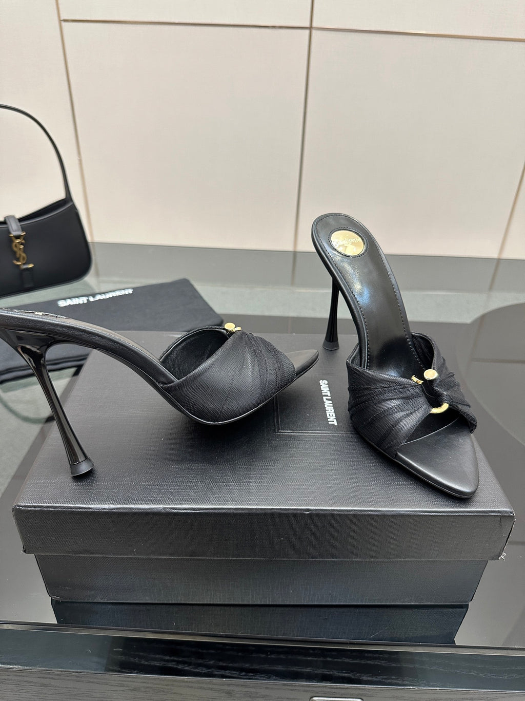 Black leather mule slides with gold accent, open toe, and stiletto heels