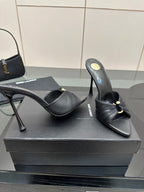 Black leather mule slides with gold accent, open toe, and stiletto heels