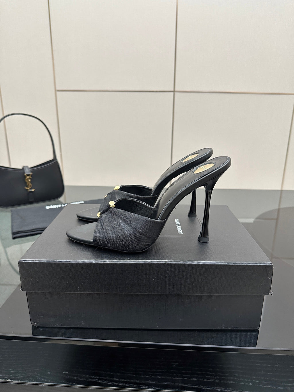 Black leather slide mules with gold hardware and sleek stiletto heels
