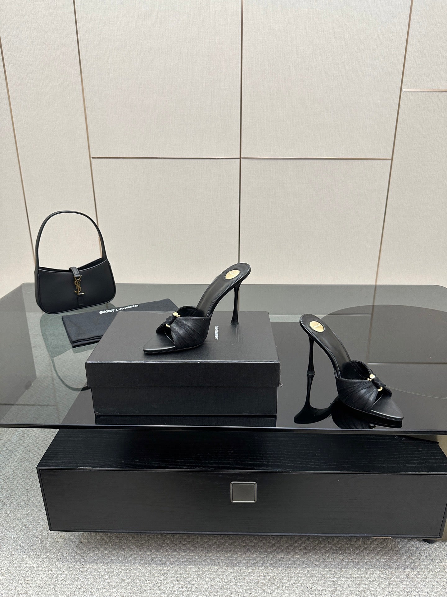 Black leather open-toe mules with gold detail and stiletto heels on display box