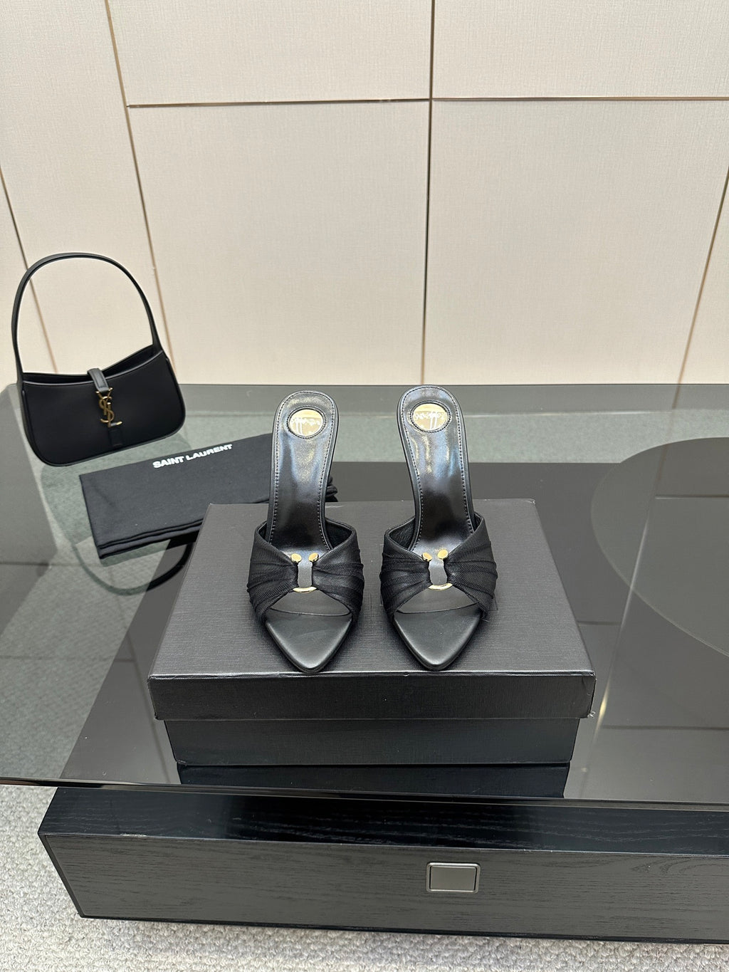 Black leather slide mules with open toe, gold accent, and stiletto heels