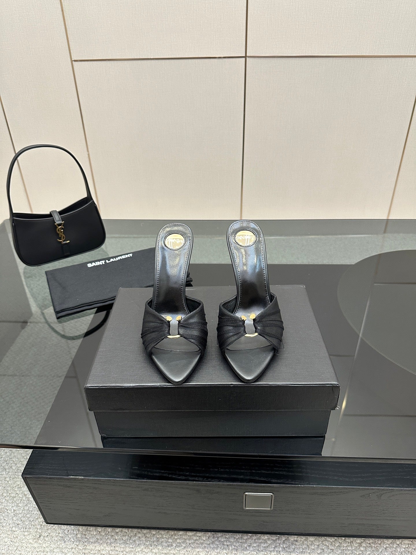 Black leather slide mules with open toe, gold accent, and stiletto heels