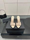 Cream heeled mule sandals with bow detail and slim stiletto heel, side view.