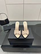 Cream heeled mule sandals with bow detail and slim stiletto heel, side view.