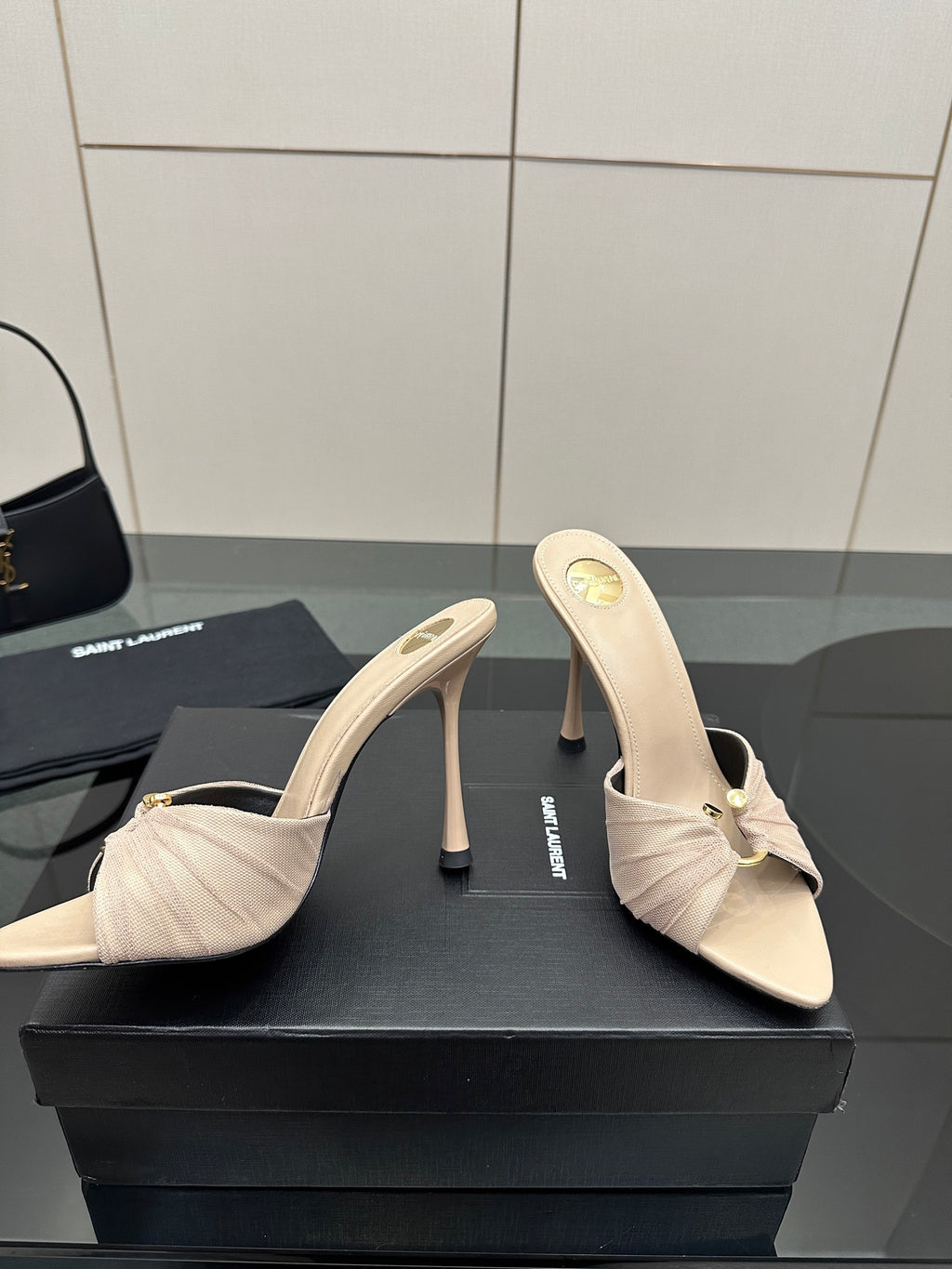 Cream heeled mule sandals with bow and stitched upper, pair shown on display.