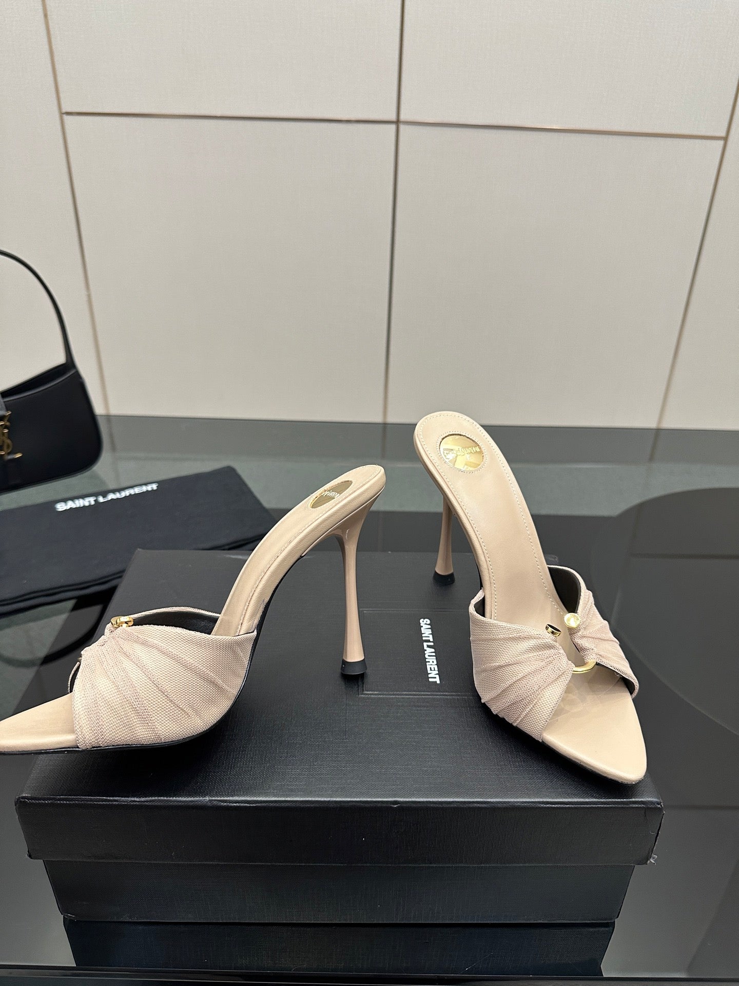 Cream heeled mule sandals with bow and stitched upper, pair shown on display.