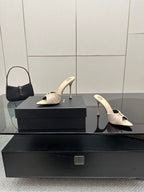 Cream heeled mule sandals with bow detail and slim stiletto heel, full pair view.
