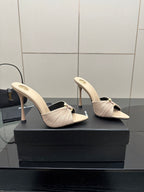 Cream heeled mule sandals with bow strap and slim stiletto heel, angled front.