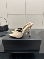 Cream heeled mule sandals with bow accent and curved back, single shoe close view.
