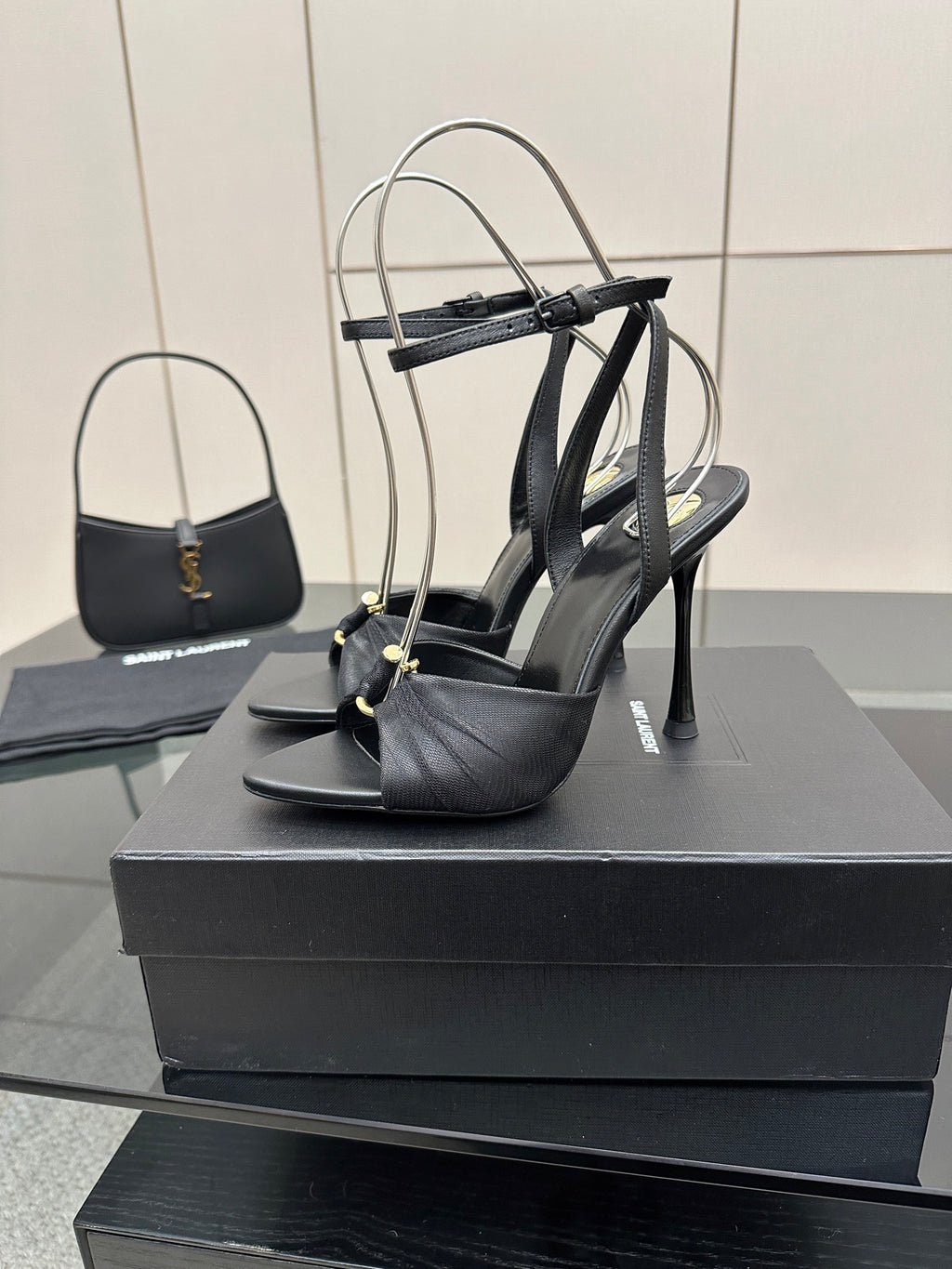 Black strappy stiletto heeled sandals with thin heel and ankle wrap, on box