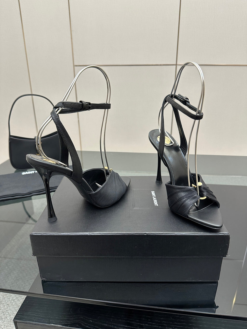 Black open-toe stiletto heeled sandals with slim heel and ankle strap, on box