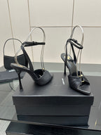 Black open-toe stiletto heeled sandals with slim heel and ankle strap, on box