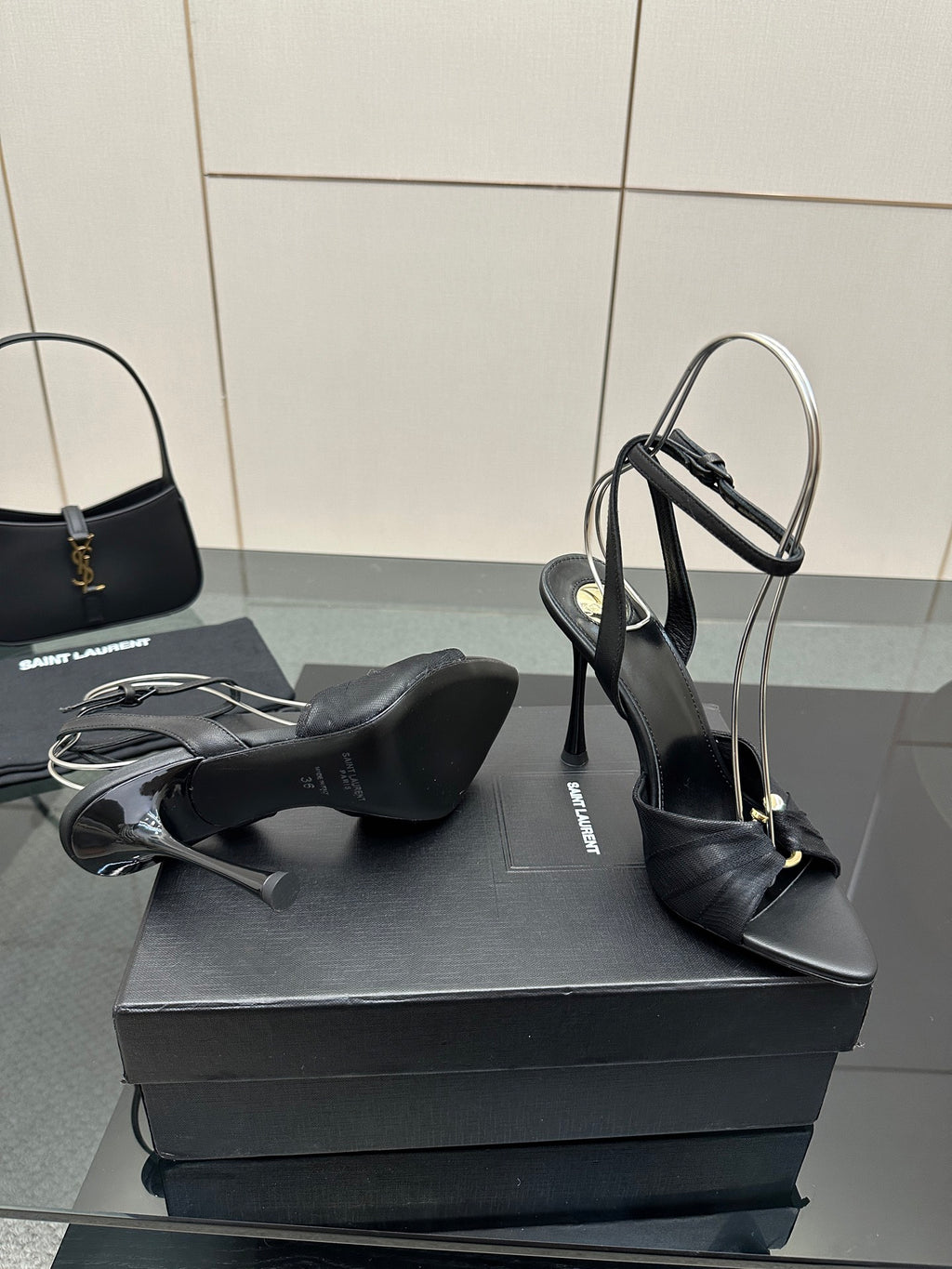 Black high-heel sandals with open toe and ankle strap, pair resting on box