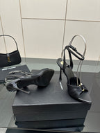Black high-heel sandals with open toe and ankle strap, pair resting on box