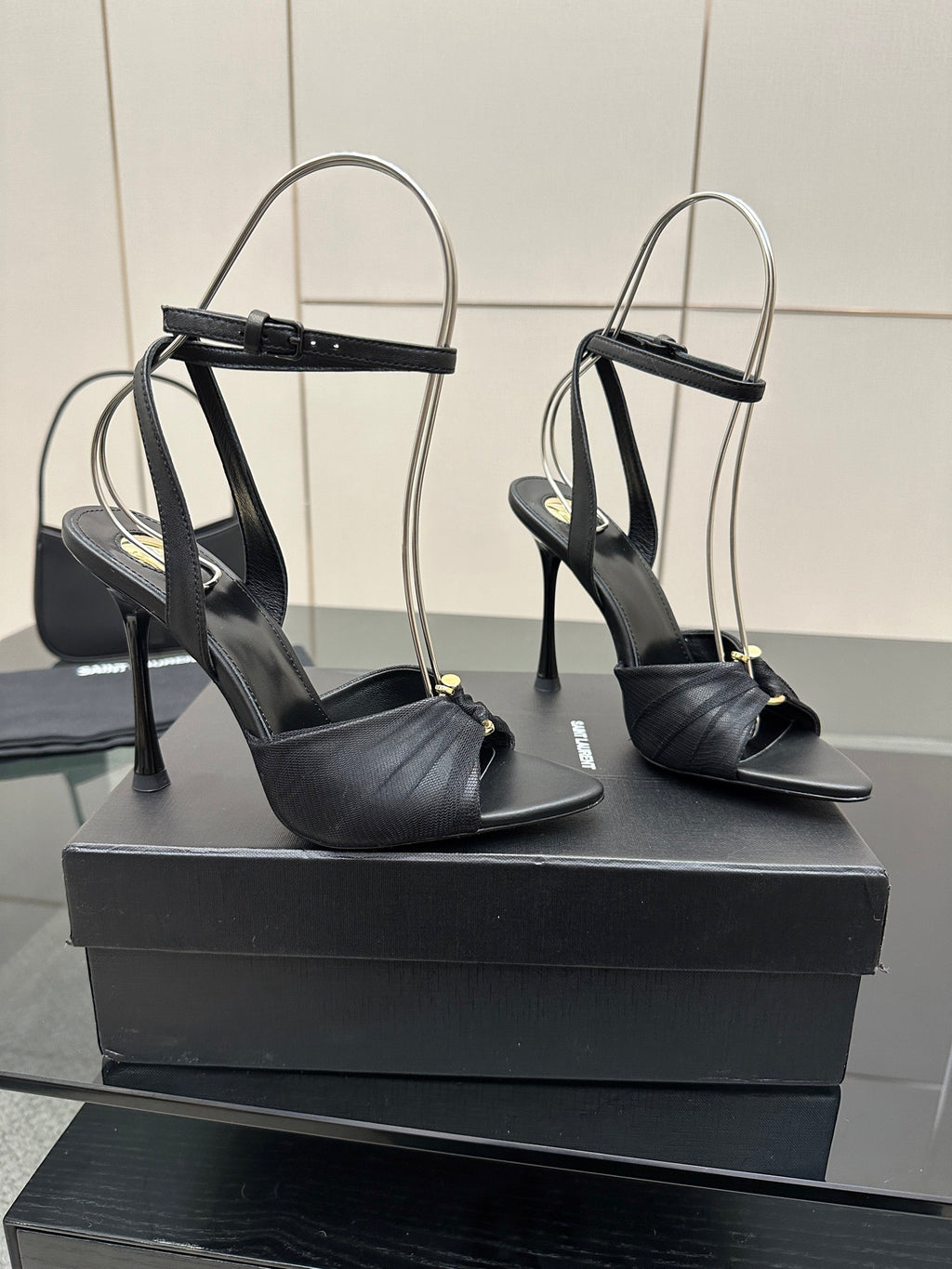 Black open-toe stiletto heeled sandals with ankle strap, shown from side angles