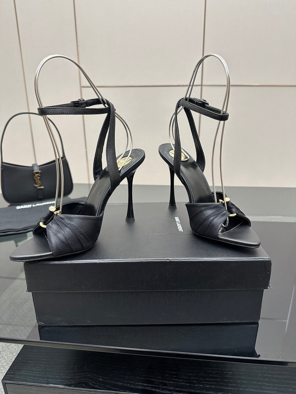 Black high-heel sandals with open toe and ankle strap, pair on display blocks