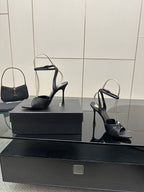 Black open-toe stiletto heeled sandals with ankle strap, single pair on box