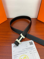Hermes reversible belt with black strap and silver buckle, laid flat