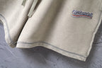 Beige shorts hem with contrast stitching and small logo patch