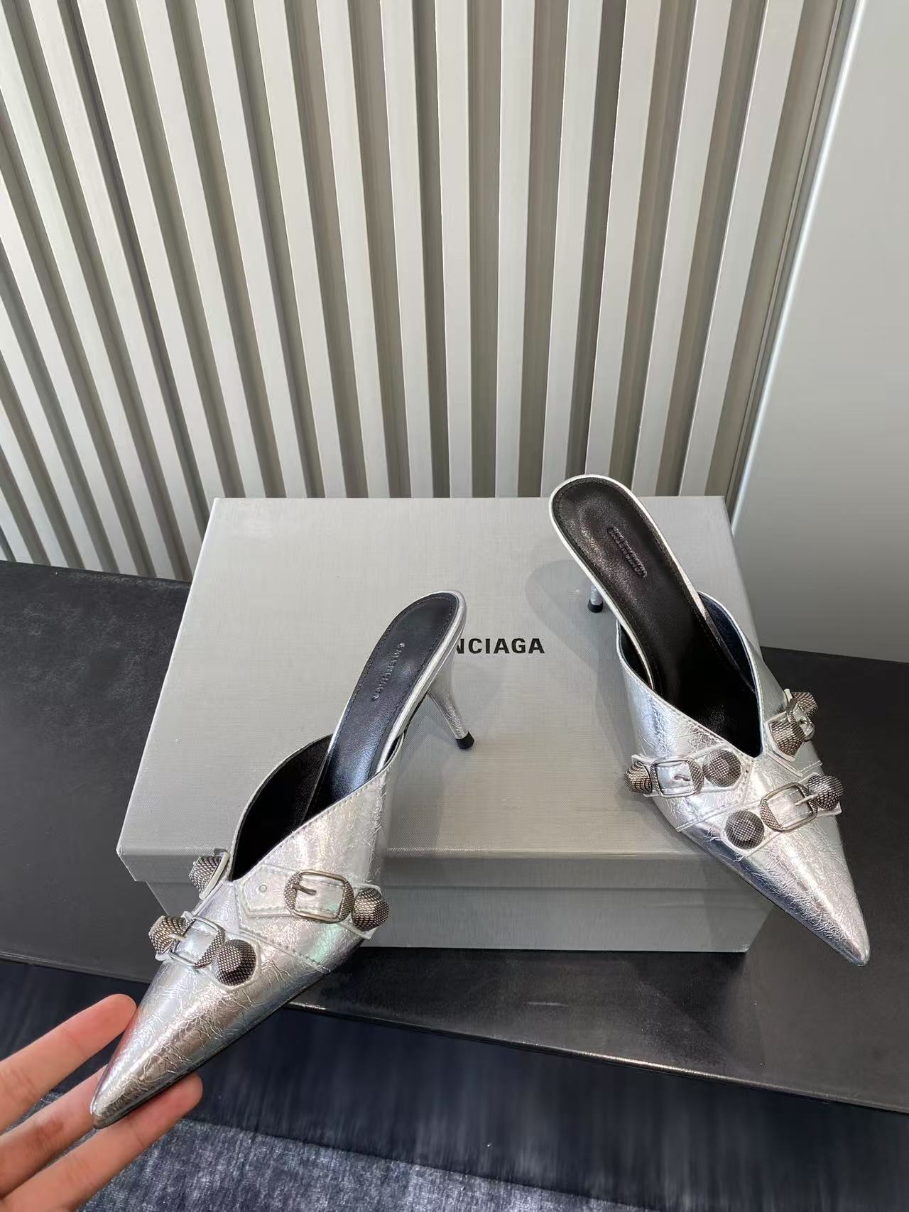 Metallic silver heeled sandals, angled view with pointed toe and buckle detail