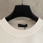 White T-shirt neckline close-up with ribbed collar and small logo patch on the inside