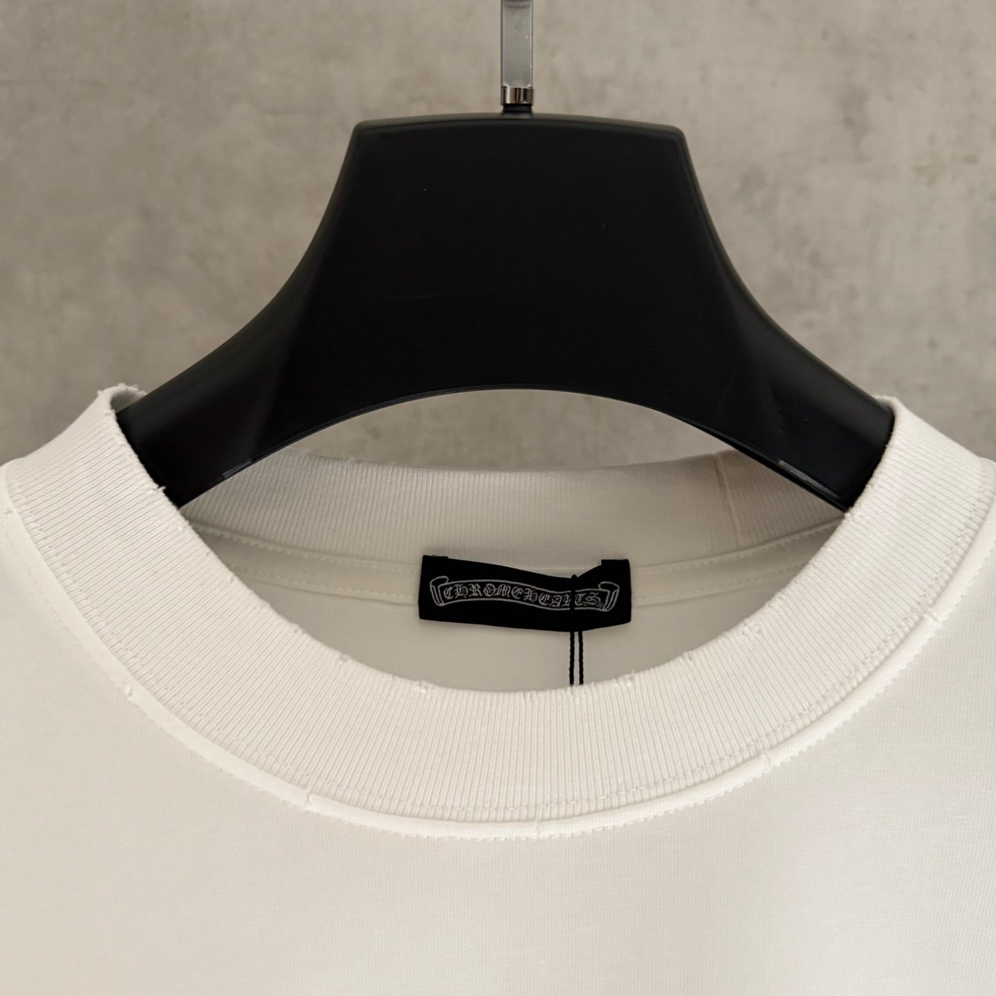 White T-shirt neckline close-up with ribbed collar and small logo patch on the inside